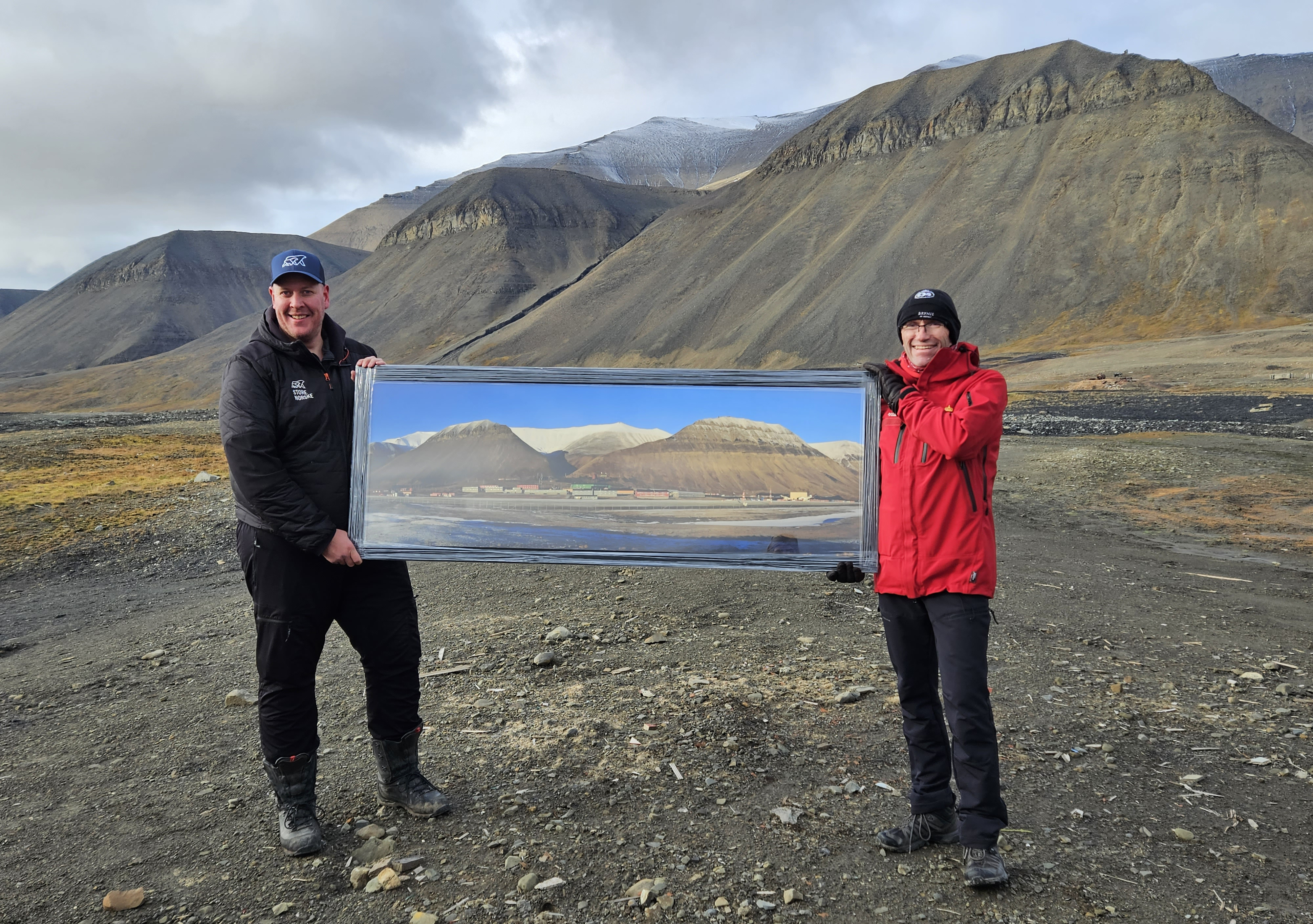 Prosjektleder Morten H. Johansen i Store Norske og klima- og miljøminister Espen Barth Eide i dagens Sveagruva med bilde av hvordan det så ut tidligere. Foto: Eva Therese Jenssen/Sysselmesteren på Svalbard. Prosjektleder Morten H. Johansen i Store Norske og klima- og miljøminister Espen Barth Eide i dagens Sveagruva med bilde av hvordan det så ut tidligere.
